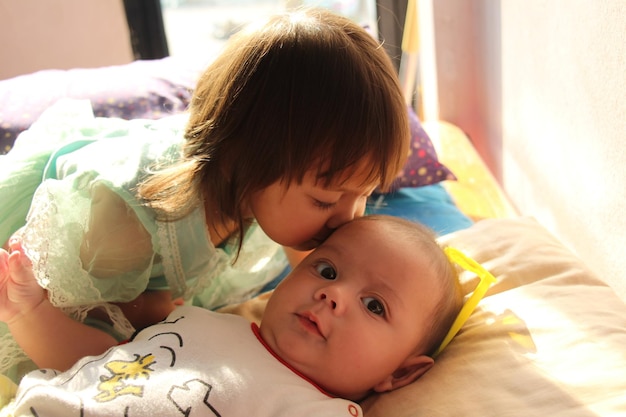 close-up of cute girl kissing brother on forehead at home