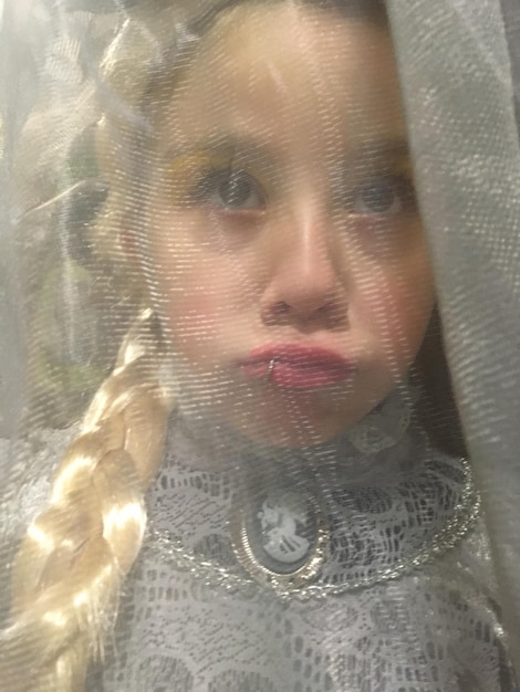 Close-up of cute girl looking through veil