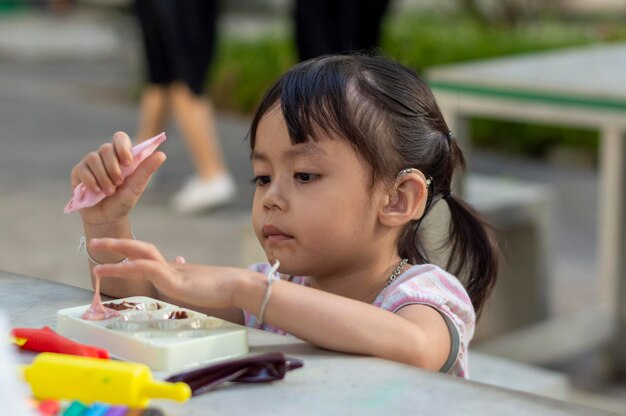 子どもたちと一緒にテーブルで粘土を遊ぶ可愛い女の子のクローズアップ