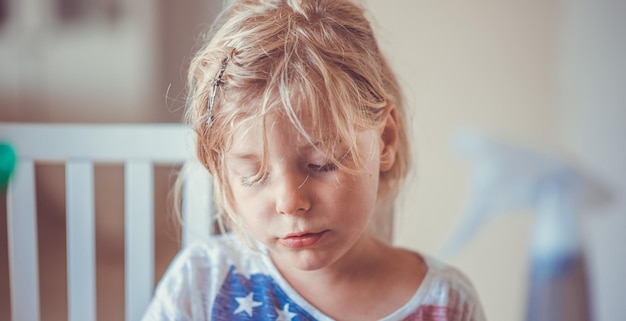 Foto prossimo piano di una ragazza carina con i capelli biondi e disordinati a casa