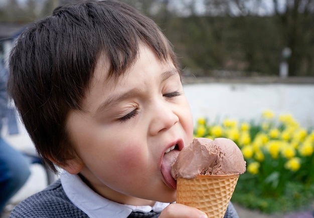 Close up of Cute kid boy eating an ice cream at the park