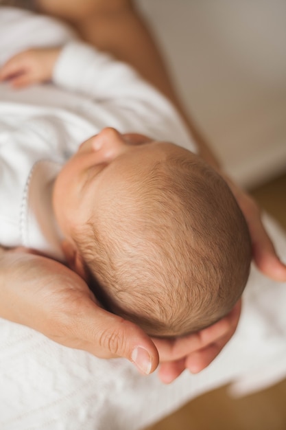 Close-up. Cute newborn baby sleeping in mother's arms. Motherhood.