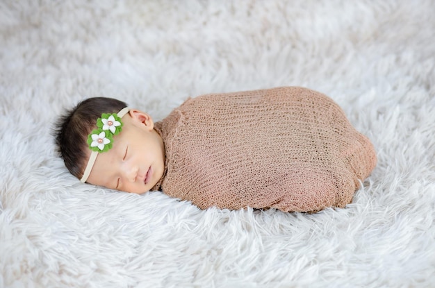 Close up cute Newborn wearing Flower headband on wool carpets, fashion concept