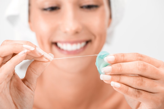 Close-up of a cute smiling girl holding dental floss. Selective focus. Focus on dental floss.