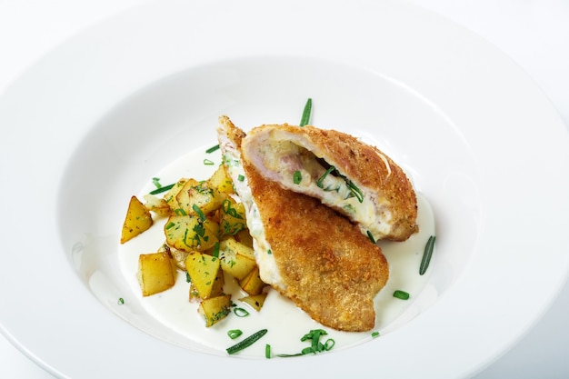 Close-up of cutting cordon bleu with cheese and turkey in crackers crumbs served with potatoes and greens