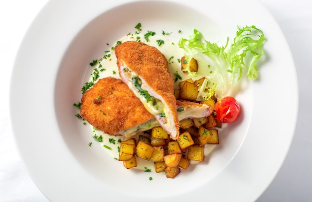 Close-up of cutting cordon bleu with cheese and turkey in crackers crumbs served with potatoes and greens