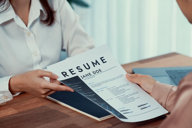 Close-up CV-papier met kwalificaties op het bureau tijdens een sollicitatiegesprek in het kantoor met jonge sollicitatiekandidaten en interviewer die over de sollicitant van de functie discussiëren Enthousiast