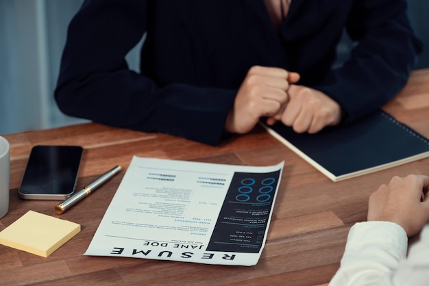 Close-up cv-papier met kwalificaties op het bureau tijdens sollicitatiegesprek op kantoor met jonge sollicitanten en interviewer bespreken over toepassing van de functie Enthousiast