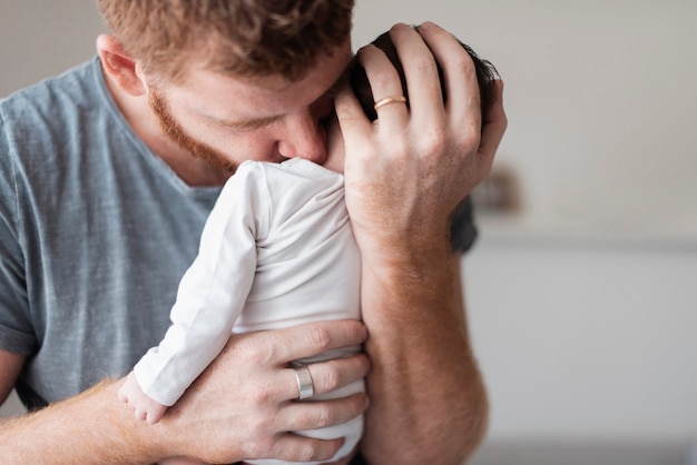 Papà del primo piano che tiene bambino con amore