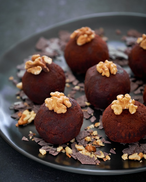 Close-up on a dark plate of rum balls with wallnutsion dark surface