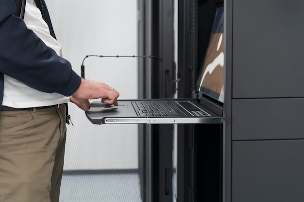 Close up on Data Center Engineer hands Using keyboard on a supercomputer. Server Room Specialist Facility with Male System Administrator Working with Data Protection Network for Cyber Security.