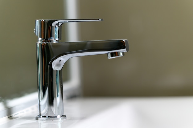 Close-up De moderne metalen kraan in de wastafelbadkamer