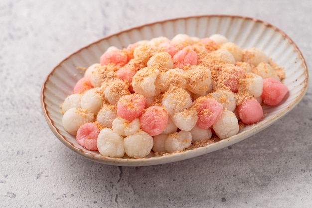 Close up of Deep-fried red and white tangyuan (tang yuan, glutinous rice dumpling balls) with peanut powder on gray table background for Winter solstice festival food.