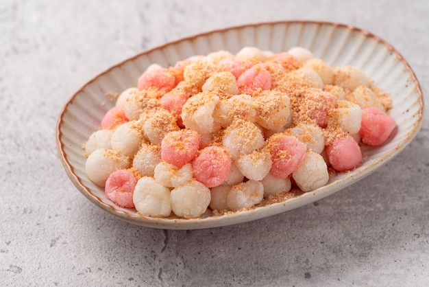 Primo piano di tangyuan rosso e bianco fritto (tang yuan, palline di gnocco di riso glutinoso) con polvere di arachidi su sfondo grigio tavolo per il cibo del festival del solstizio d'inverno.