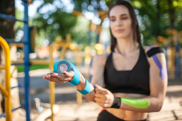 Close up of defocused woman holding colorful rolls of elastic kinesiology tapes