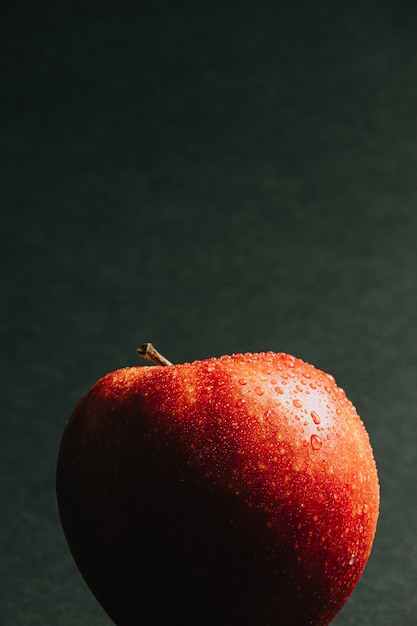 Крупным планом вкусное яблоко с каплями воды на темном фоне