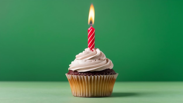 Close up of delicious cupcake with burning candle on green background