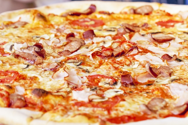 Close-up of Delicious Fresh Pizza with mushrooms, Bavarian sausages and ham