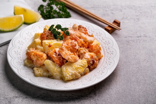 Close up of delicious fried shrimp balls with pineapple and mayonnaise sauce in a white plate on gray table