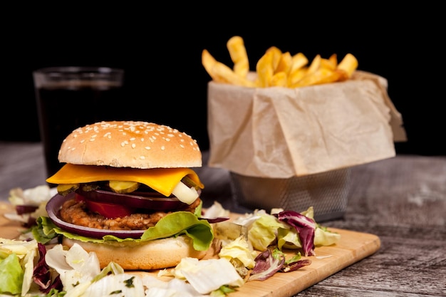 Primo piano di deliziosi hamburger fatti in casa su un piatto di legno accanto alle patatine fritte. fast food. spuntino malsano