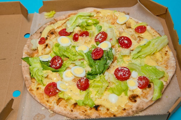 Close up of delicious hot pizza in cardboard box on light blue background Selective focus