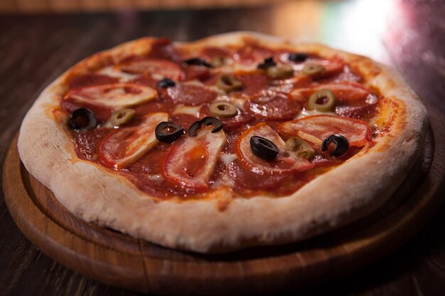 Close up of delicious meat pizza with salami and tomatoes