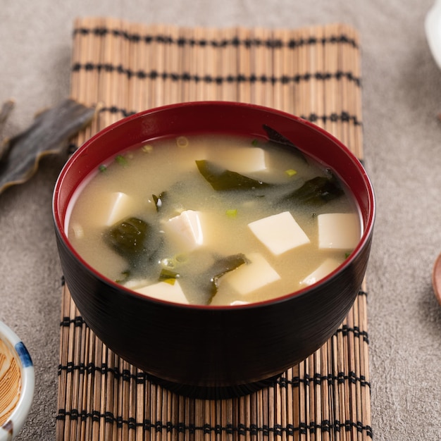 Крупный план вкусного пикантного японского супа мисо в черной миске для еды