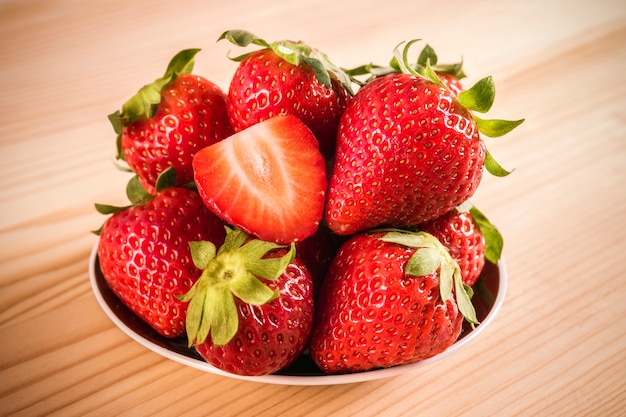 Close up of a delicious strawberries ready to eat in a plate on a wooden table