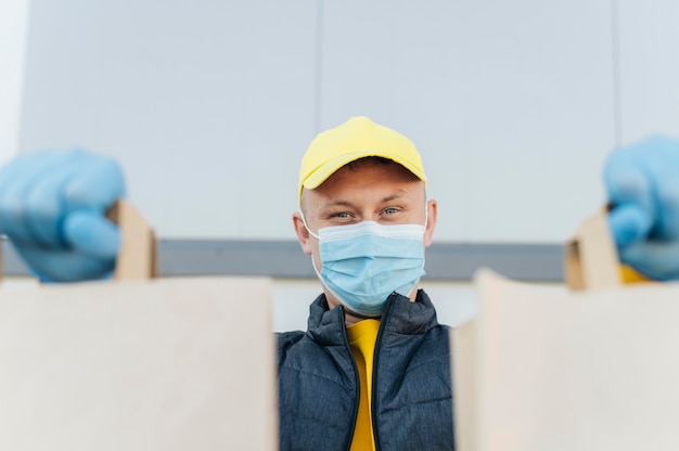 Photo close-up delivery man holding bags