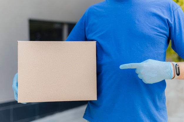 Close-up delivery man pointing at box