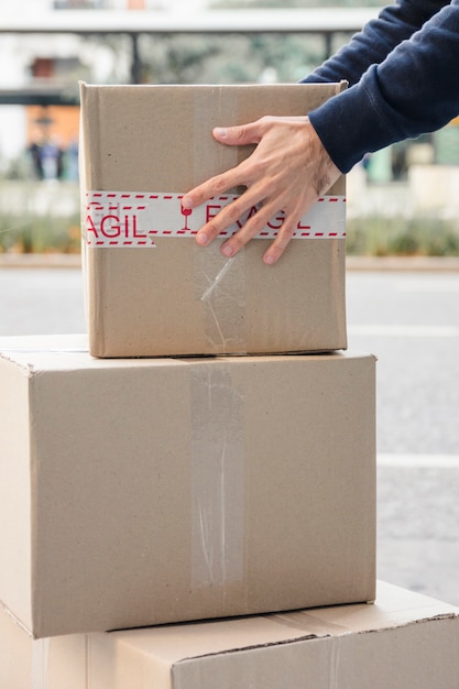 Photo close-up of a delivery man's hand carrying cardboard box