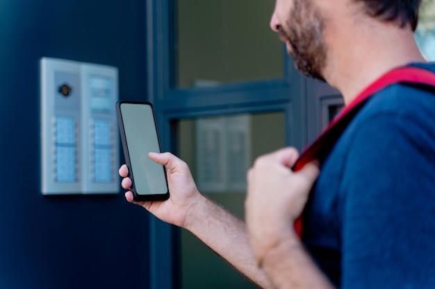 Close up of delivery man with smartphone delivering parcel box . Technology and courier service concept. Horizontal view of unrecognizable rider delivering home a package.