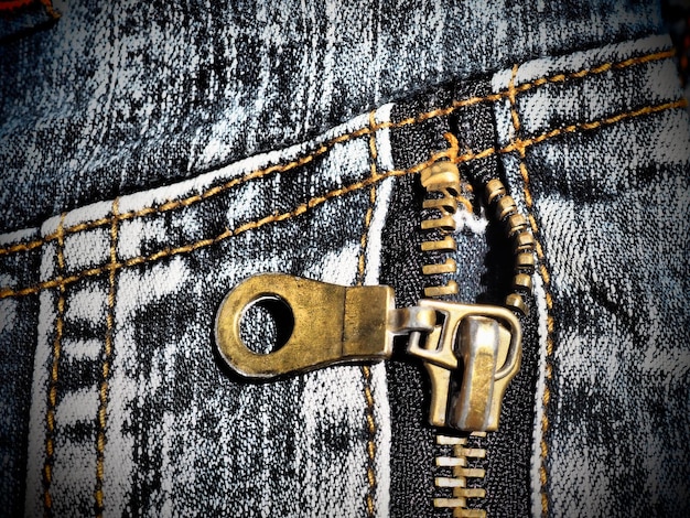 Close-up denim met naden en sloten Zwaar sjofele versleten jeans Metalen bronsgeel slot met runner Verticale naden