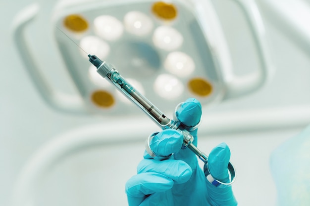 Close-up of a dentist's hand holding an injection syringe for a patient in the office.