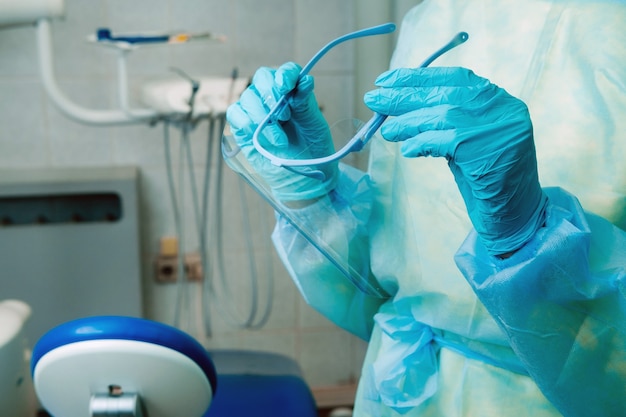 Close up of a dentist's hands holding a protective plastic screen in his office.