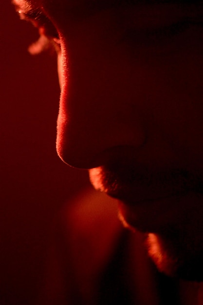 Foto close-up di un uomo depresso in una stanza illuminata di rosso