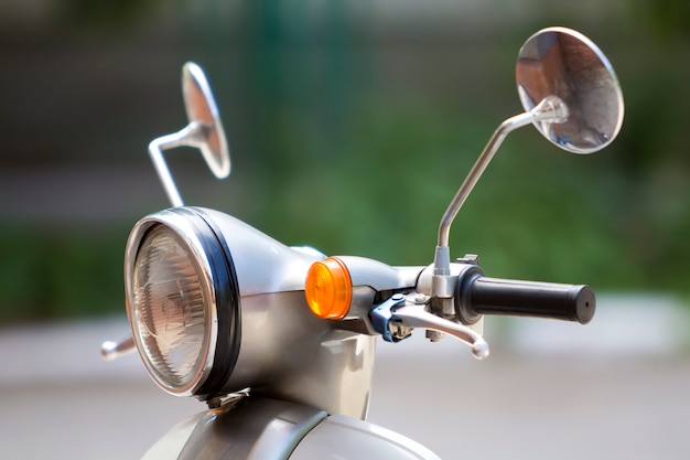 Close-up detail of new white shiny motorbike with round headlight