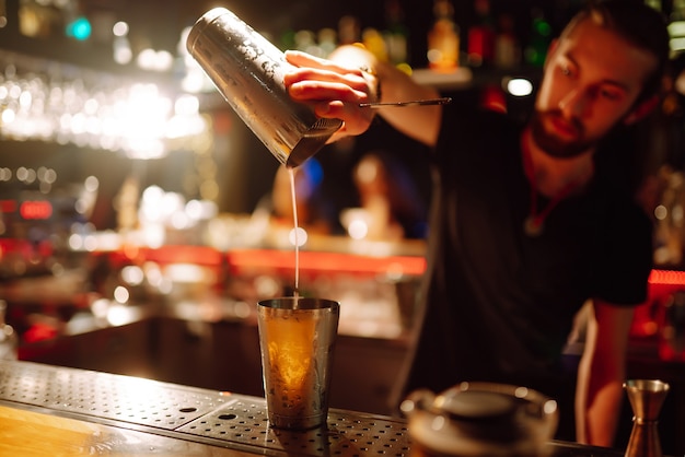 Close-up detail van barman maakt een cocktail in een nachtclubProfessionele barman die een shaker schenkt