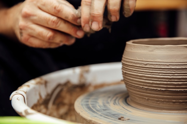 Close up detail view at an artist makes clay pottery on a spin wheel