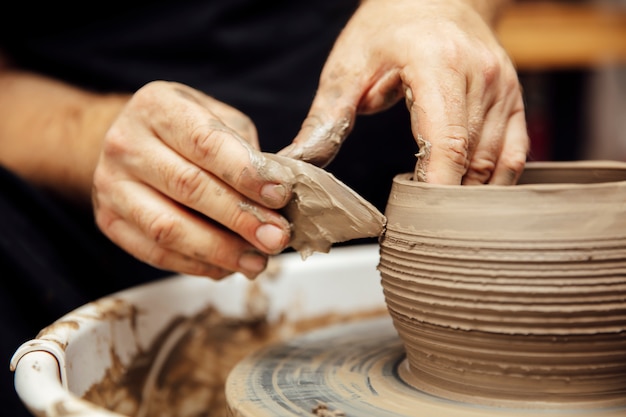 Close up detail view at an artist makes clay pottery on a spin wheel