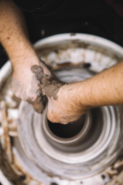 Close up detail view at an artist makes clay pottery on a spin wheel