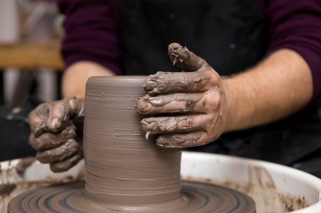 Close up detail view at an artist makes clay pottery on a spin wheel