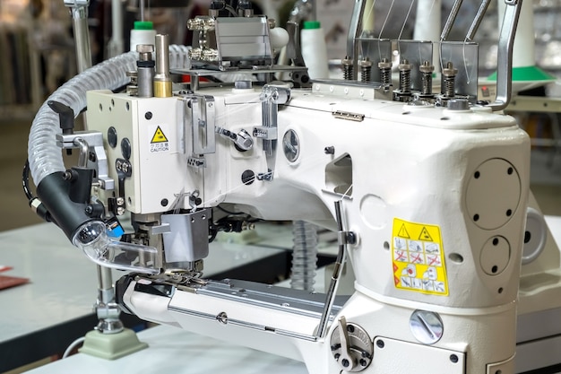 Close-up of details of modern white professional electric sewing machine on a table in factory. Work place of seamstress. No People.