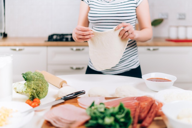 Close up details of pregnant woman preparing pizza and making dough