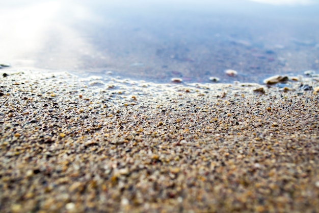 Close up details of a sandy beach small pebbles shining at sunrise on a mediterranean island morning...