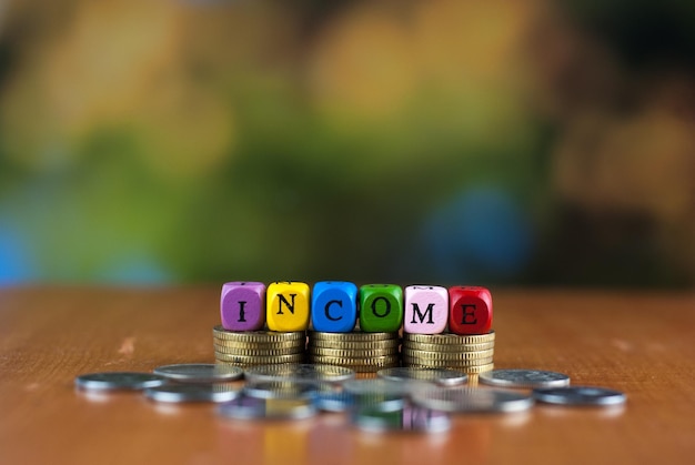 Close-up of dices with income text over coins on table