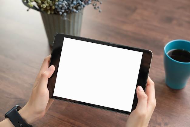 Foto close-up die van hand zwarte tablet en koffie op lijstbureau houden.