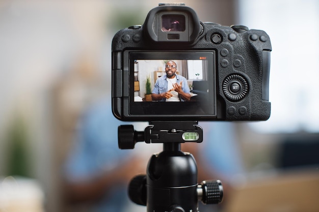 Крупный план цифровой камеры с африканским блоггером на экране
