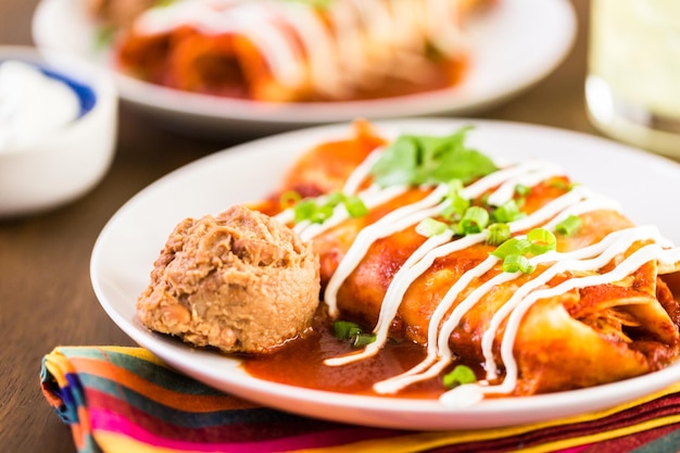 Close up of dinner plate with Chicken enchiladas garnished with green onions and sour cream.