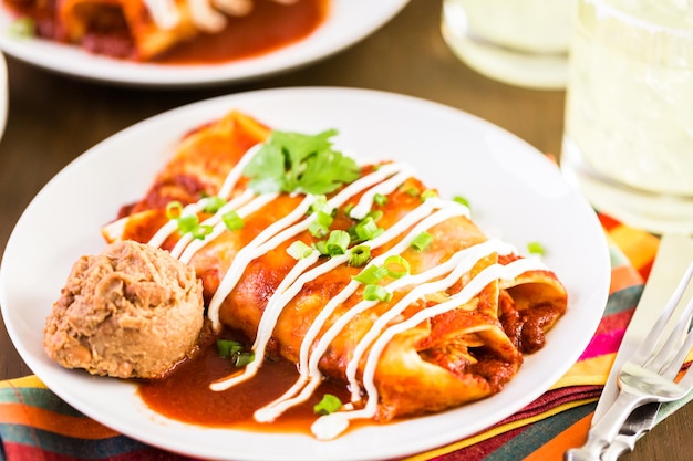 Close up of dinner plate with Chicken enchiladas garnished with green onions and sour cream.